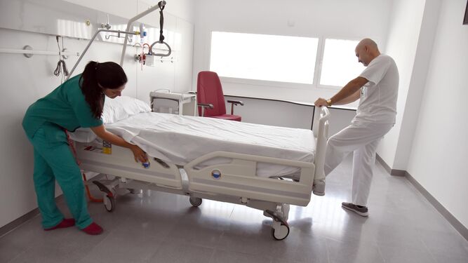 Dos trabajadores del SAS preparan una de las habitaciones del hospital de La Línea.