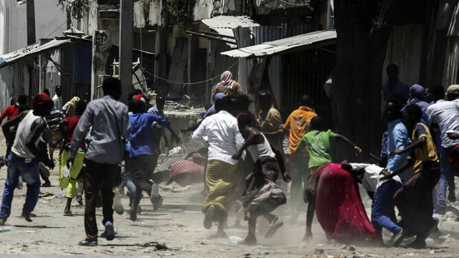 Varios somalíes corren tras la explosión de uno de los coches bomba.