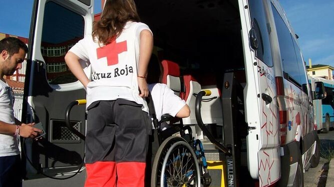 Una voluntaria ayuda a una persona a entrar en una furgoneta de Cruz Roja.