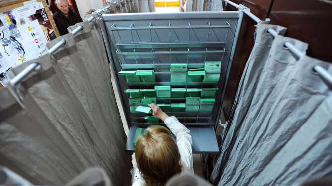 Una imagen de archivo de papeletas con distintas candidaturas colocadas en una cabina, en un colegio electoral.