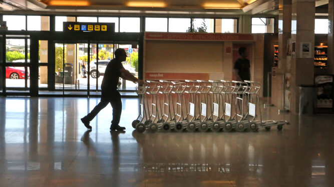 Un trabajador del aeropuerto transporta una carritos por la terminal.