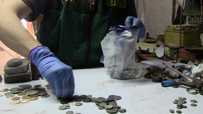 Un agente de la Guardia Civil guarda varias de las monedas intervenidas.
