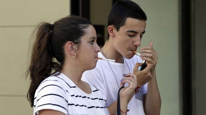 Un par de menores de 20 años, fumando por la calle