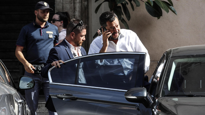 El viceprimer ministro italiano, Matteo Salvini, en el centro de la imagen, abandona su domicilio en Roma.