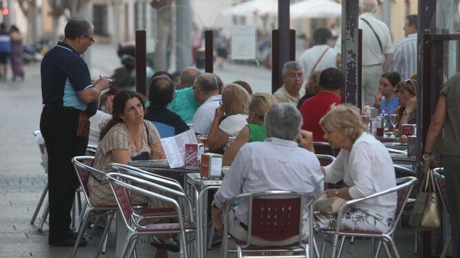 Un camarero atiende a unos clientes en una terraza de San Fernando.