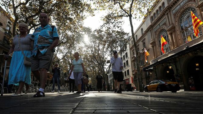 Varios turistas pasean por la Rambla de Barcelona.