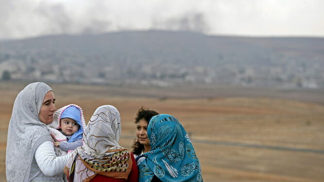 Un grupo de mujeres y sus hijos observan  los ataques a la ciudad kurdo siria de Koban, en una imagen de archivo