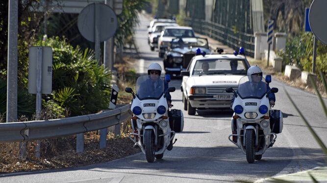 El Rolls Royce escoltado por coches policiales australianos cruza el puente de hierro de Guadiaro.