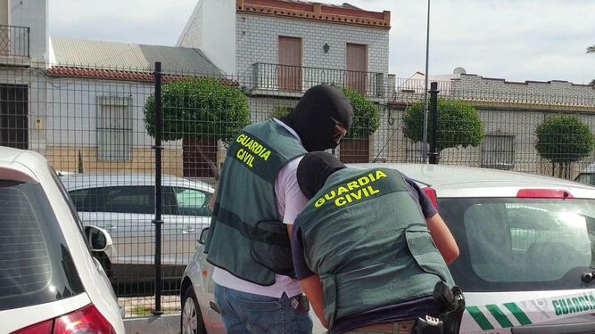 Dos agentes de la Benemérita precintan uno de los vehículos requisados en la operación.