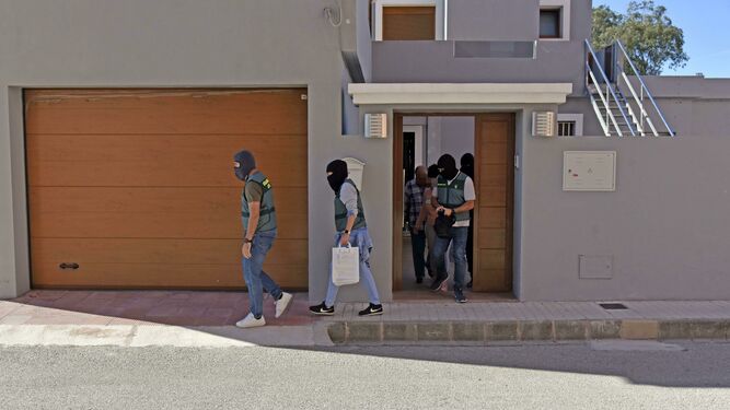 Varios agentes conducen a uno de los detenidos en su casa, en Campamento (San Roque)