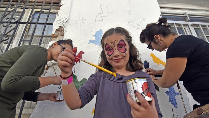 Una niña participa en el embellecimiento de una fachada en Cayetano del Toro, este sábado.