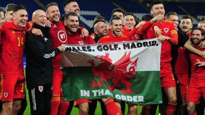Bale se ríe a carcajadas mientras posa con la bandera que sostienen sus compañeros.