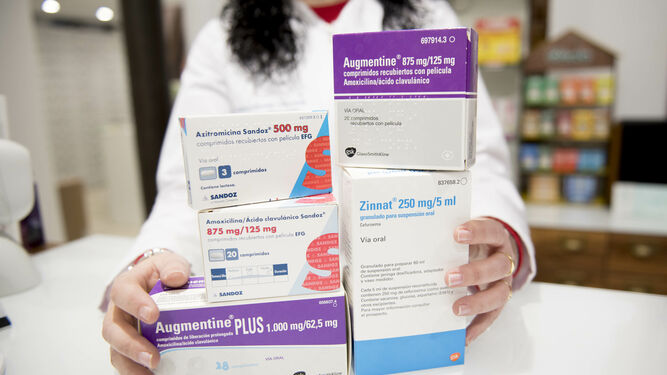 Una farmacéutica muestra varias presentaciones de antibióticos en una farmacia.