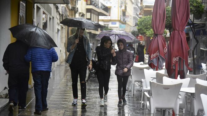 Varios ciudadanos caminan bajo paraguas en Algeciras.