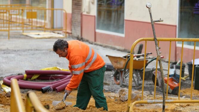 Un operario trabaja en un obra en mitad de una calle de Sevilla.
