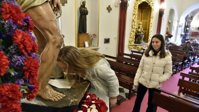 Una mujer besa el pie de Jesús Atado a la Columna en Algeciras con la protección de un pañuelo.