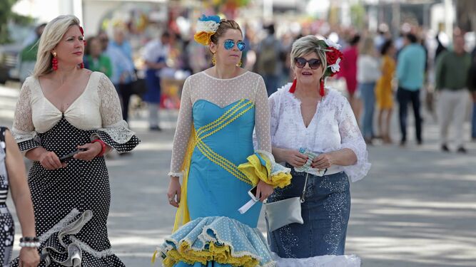 Tres mujeres vestidas de flamenca pasean por la Feria de Los Barrios en la pasada edición.