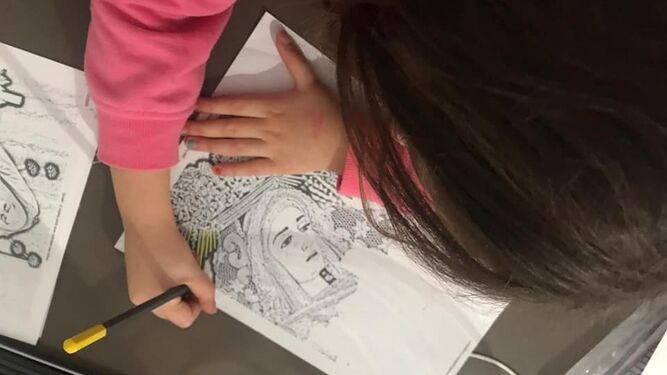 Una niña colorea una de las imágenes distribuidas por la hermandad de Flagelación y Estrella