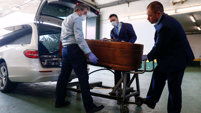 Trabajadores de los Servicios Funerarios de Madrid introducen un féretro en un vehículo en el Tanatorio M-30.