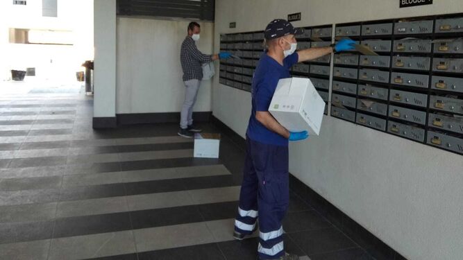 Trabajadores municipales depositas los sobres con mascarillas en buzones