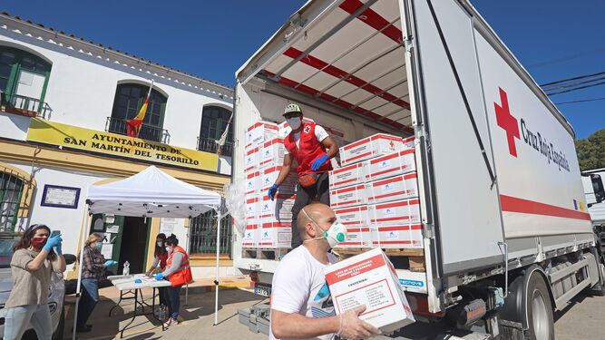 Voluntarios de la Cruz Roja descargan cajas con alimentos junto al Ayuntamiento de Tesorillo, este miércoles.