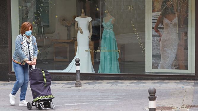 Una mujer camina delante de un negocio de vestidos de novia y acompañantes, en Algeciras.