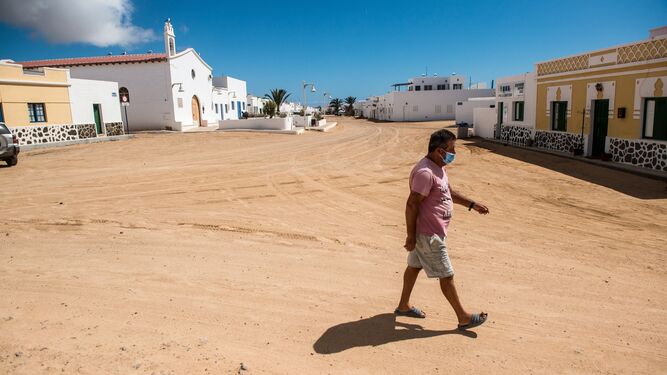 Un vecino graciosero, con mascarilla, por las calles de arena de La Caleta del Sebo