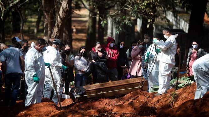 Sepultureros entierran un féretro en una fosa en Sao Paulo