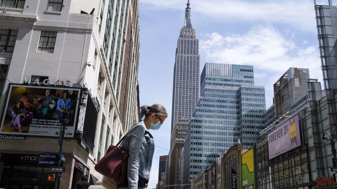 Una mujer pasea por Manhattan con guantes y mascarilla.