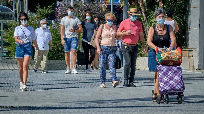 Un grupo de personas con mascarillas por la calle.