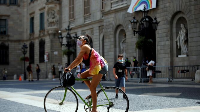 Una joven en bicicleta con mascarilla en el centro de Barcelona.