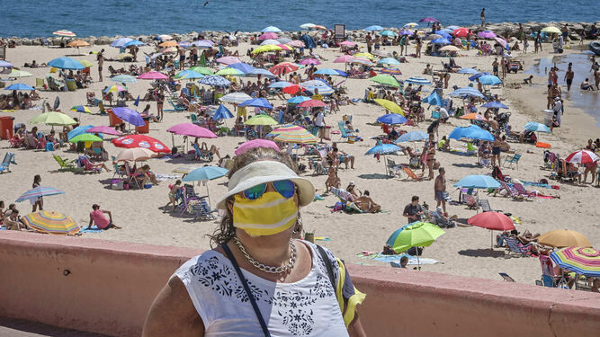 Una mujer espera para entrar en la playa de Santa María del Mar.