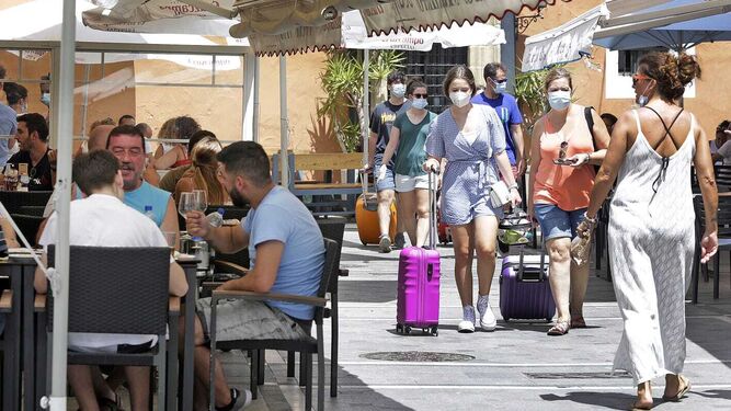 Turistas con mascarilla pasean junto a varias terrazas en El Puerto.