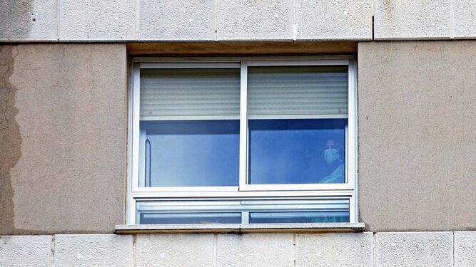 Una enferma, protegida con una máscara, asomada a una ventana del Punta de Europa