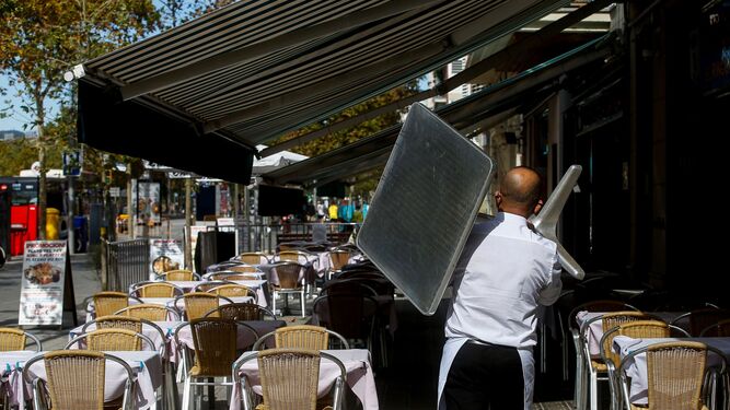 Un camarero recogiendo una mesa de una terraza de un restaurante del barrio de la Barceloneta de Barcelona este jueves.