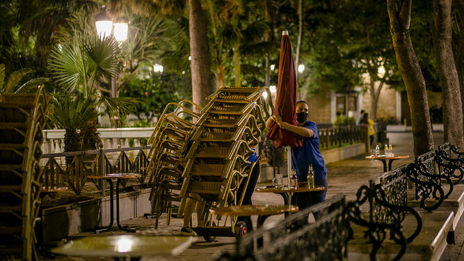 Una camarera recoge las mesas de una terraza en Cádiz