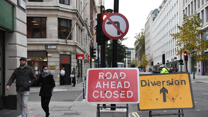 Una pareja camina junto a un cartel que indica que la carretera está cerrada en el centro de Londres.