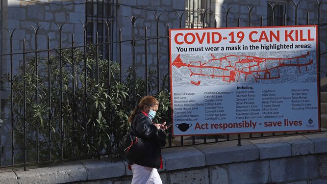 Una persona pasa junto a un cartel sobre la Covid en Gibraltar