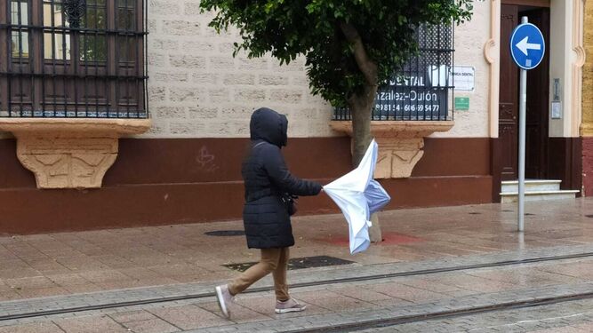 Un mujer con problemas  por el viento por la calle Real de San Fernando.