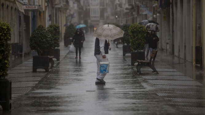 Personas con paraguas durante el pasado temporal en una céntrica calle gaditana.