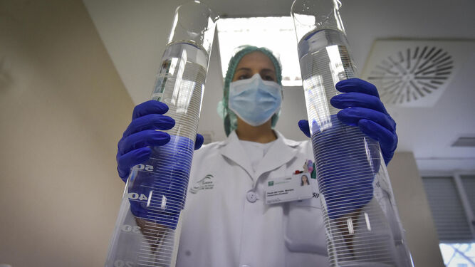 Una sanitaria sostiene dos matraces en el laboratorio de un hospital.