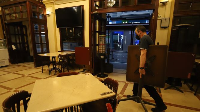 Un camarero del céntrico Café Modelo de La Línea carga con una mesa de la terraza.