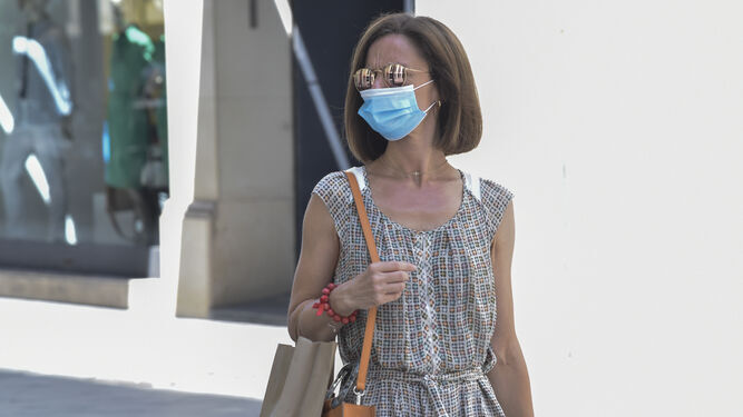 Una mujer, paseando con una mascarilla higiénica