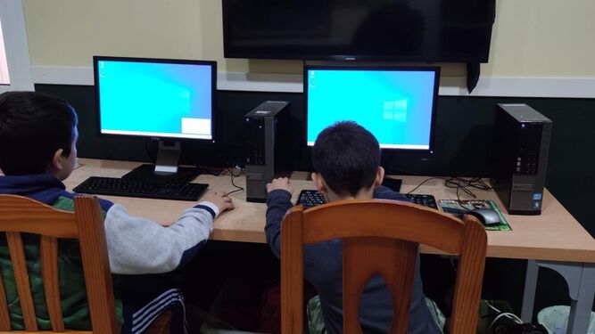 Dos niños, con los ordenadores donados por la empresa.