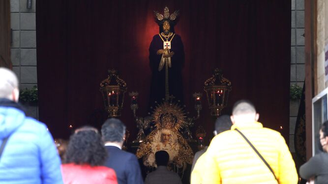 Varias personas rezan ante las imágenes del Medinaceli y la Virgen de la Trinidad de La Línea.