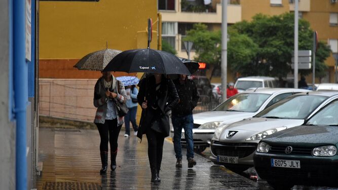 Unos algecireños pasean por Algeciras con sus paraguas.