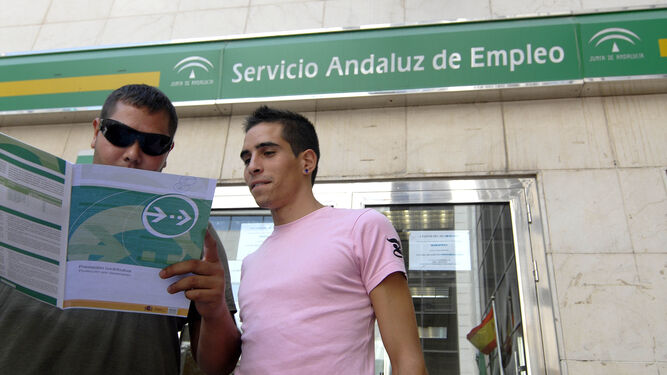 Dos jóvenes frente a una sede del Servicio Andaluz de Empleo.