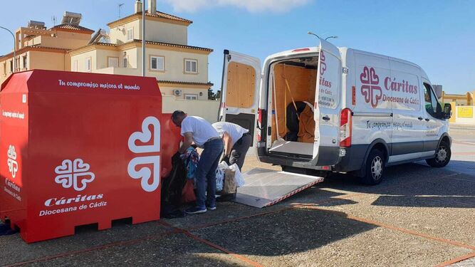 Empleados de la empresa Inserta Cádiz, de Cáritas, recogen la ropa de uno de los contenedores.