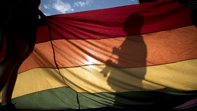 Silueta de un hombre sobre la bandera arcoíris.