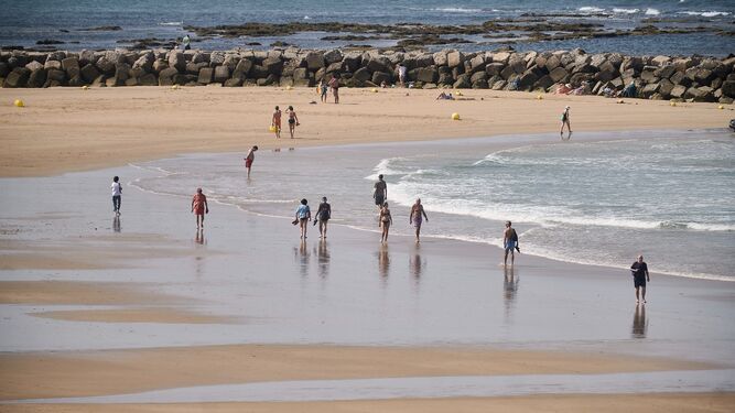 Varias personas pasean por la playa de Santa María del Mar.